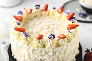 Rezept für festliche Erdbeer Kokos Torte mit Mascarpone. Getränkt mit Kokosmilch und dekoriert mit essbaren Blüten. Super schön dekorierte sommerliche Torte, perfekt als Geburtstagstorte! #Erdbeer #Kokos #Torte #Dekoration #Tortendekoration #Erdbeeren #Geburtstagstorte