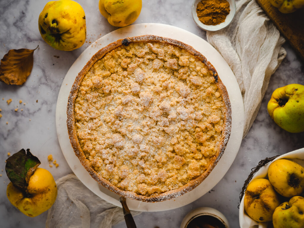 Wärmendes Rezept für saisonalen Quittenkuchen für die kalte Jahreszeit. Dieser Quitten Streuselkuchen mit gebackener Vanillecreme ist einfach eine tolle Art um Quitten zu verwerten ohne sie zu Quittengelee oder Quittenmus verarbeiten zu müssen. #Quitten #Quittenkuchen #saisonal #regional #Quittenverwertung #Streuselkuchen