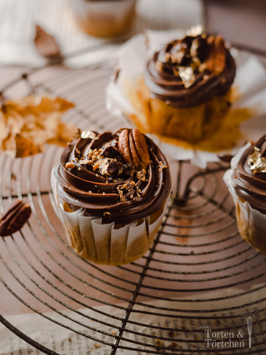 Ein einfaches Rezept für herbstliche Pumpkin Spice Cupcakes mit gebrannten Pekannüssen. Die karamellisierten Nüsse auf einer reichen Schokoadencreme passen einfach so gut zu dem gewürzten saftigen Kürbismuffin! #Pumpkinspice #backen #Rezept #Kürbis #Herbstrezepte #Nüsse #Muffins #Cupcakes