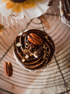 Ein einfaches Rezept für herbstliche Pumpkin Spice Cupcakes mit gebrannten Pekannüssen. Die karamellisierten Nüsse auf einer reichen Schokoadencreme passen einfach so gut zu dem gewürzten saftigen Kürbismuffin! #Pumpkinspice #backen #Rezept #Kürbis #Herbstrezepte #Nüsse #Muffins #Cupcakes