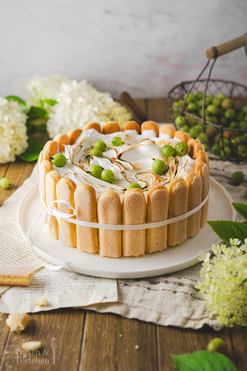 Saisonales Rezept für eine köstliche Stachelbeer-Charlotte mit Baiserhaube. Der saftige Biskuitboden wird mit herber Zitronenlimonade durchtränkt und umhüllt eine fruchtige Stachelbeerfüllung. Eine luftige Baiserhaube, leicht flambiert, verleiht dem Dessert einen besonderen Abschluss. #Stachelbeeren #Stachelbeertorte #Baiser #Rezept #Torte