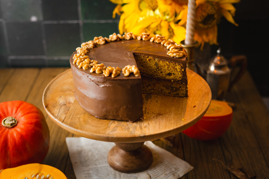 Ein einfaches Rezept für einen herbstlichen rustikalen mit Zimt, Muskat und Orange gewürzten Kürbiskuchen verfeinert mit Nüssen und mit einer samtigen herben Schokoladenganache, die die Zimtnoten der Pumpkin Spice Böden perfekt komplementiert. #herbstkuchen #herbstrezepte #pumpkinspice #kürbis #rezepte #backen