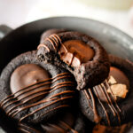 Diese Schoko-Orangen Thumbprint Cookies vereinen feine Zartbitterschokolade mit der fruchtigen Frische kandierter Orangenschalen. Gefüllt mit einer cremigen Ganache und dekoriert mit edler Schokolade sind sie ein Highlight für jeden Plätzchenteller und perfekt für die Weihnachtszeit. Einfach in der Zubereitung und beeindruckend im Geschmack – diese Plätzchen sind ein Muss für alle Schokoladenliebhaber! #Weihnachtsplätzchen #Schokocookies #Weihnachtsbäckerei #Thumbprintcookies #weihnachten #backe #Rezept