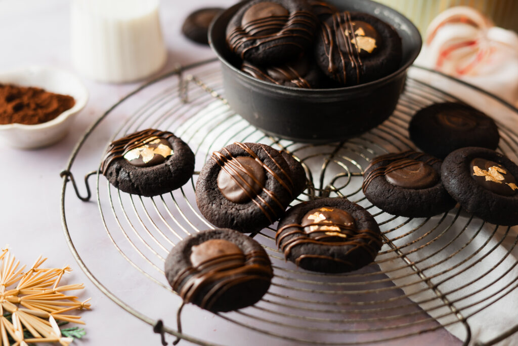 Diese Schoko-Orangen Thumbprint Cookies vereinen feine Zartbitterschokolade mit der fruchtigen Frische kandierter Orangenschalen. Gefüllt mit einer cremigen Ganache und dekoriert mit edler Schokolade sind sie ein Highlight für jeden Plätzchenteller und perfekt für die Weihnachtszeit. Einfach in der Zubereitung und beeindruckend im Geschmack – diese Plätzchen sind ein Muss für alle Schokoladenliebhaber! #Weihnachtsplätzchen #Schokocookies #Weihnachtsbäckerei #Thumbprintcookies #weihnachten #backe #Rezept