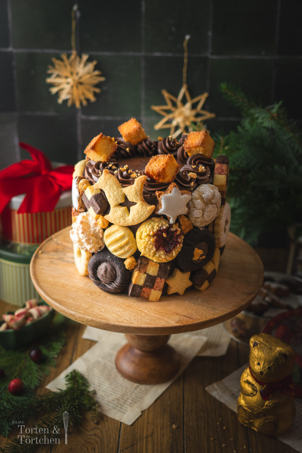 Eine festliche Torte im Germknödel-Stil mit Mohnböden, cremiger Vanillesauce, fruchtigem Pflaumenmus und einer edlen Schokoladenganache. Verziert mit Weihnachtsplätzchen – ideal, um Gäste zu begeistern oder Plätzchenreste kreativ zu verwerten. #Weihnachtstorte #Weihnachtsbäckerei #Backen #Rezept #Weihnachtsplätzchen #Plätzchen