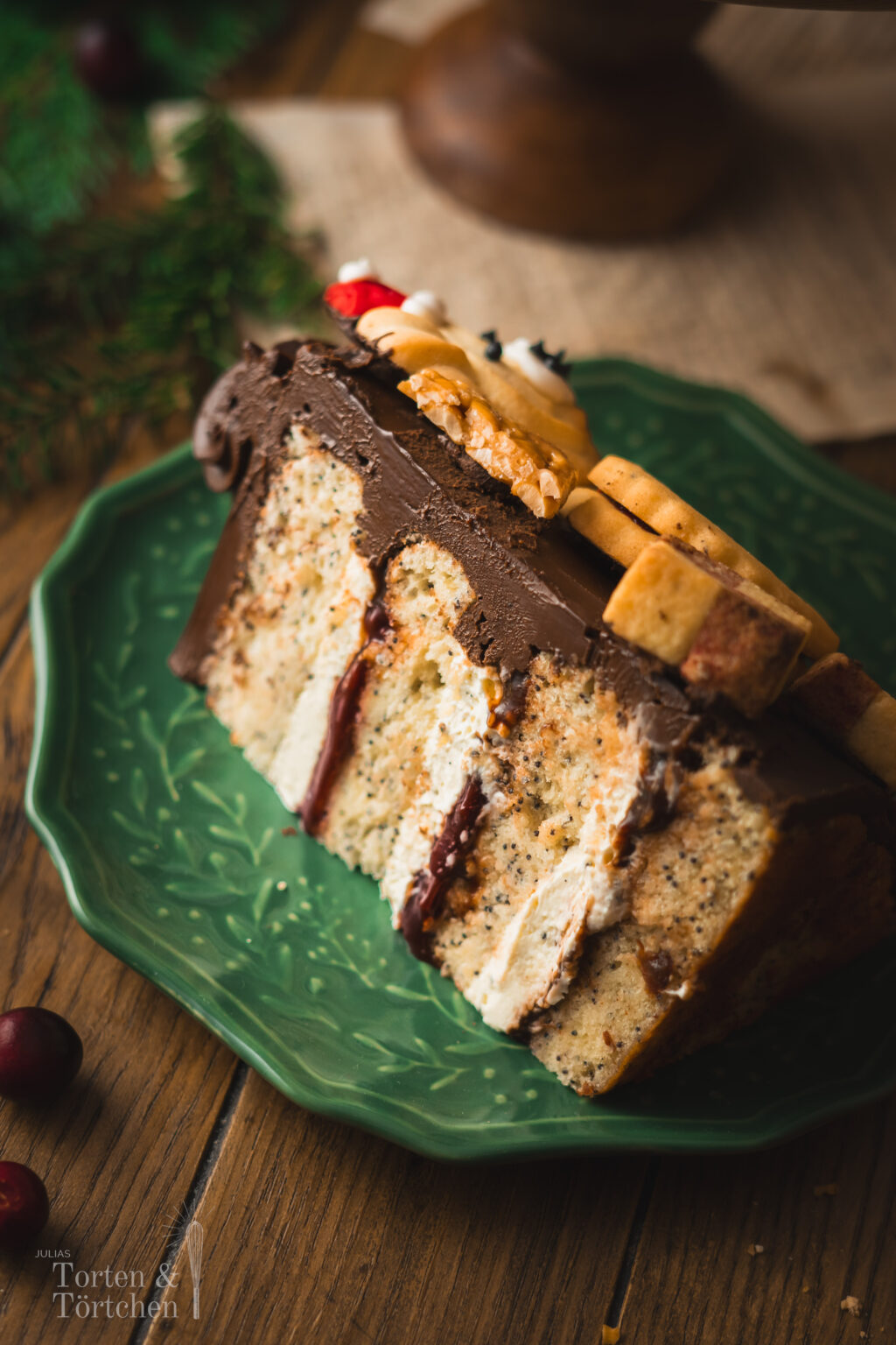 Eine festliche Torte im Germknödel-Stil mit Mohnböden, cremiger Vanillesauce, fruchtigem Pflaumenmus und einer edlen Schokoladenganache. Verziert mit Weihnachtsplätzchen – ideal, um Gäste zu begeistern oder Plätzchenreste kreativ zu verwerten. #Weihnachtstorte #Weihnachtsbäckerei #Backen #Rezept #Weihnachtsplätzchen #Plätzchen