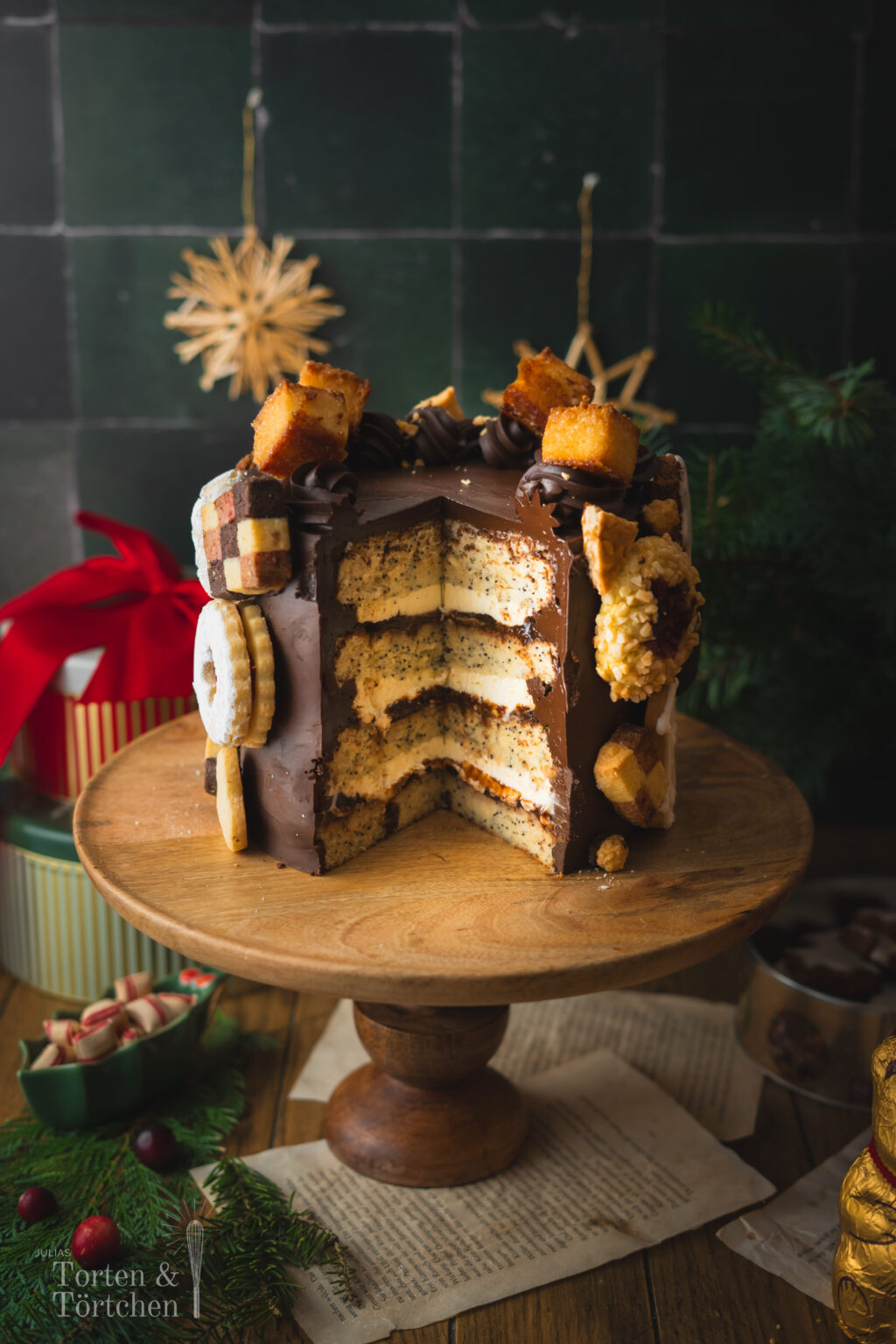 Eine festliche Torte im Germknödel-Stil mit Mohnböden, cremiger Vanillesauce, fruchtigem Pflaumenmus und einer edlen Schokoladenganache. Verziert mit Weihnachtsplätzchen – ideal, um Gäste zu begeistern oder Plätzchenreste kreativ zu verwerten. #Weihnachtstorte #Weihnachtsbäckerei #Backen #Rezept #Weihnachtsplätzchen #Plätzchen