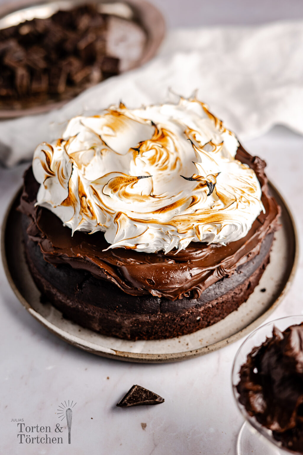 Ein einfaches Rezept für einen super saftigen und fudgy Heiße Schokoladen Kuchen. Der Boden ist wie ein Mix aus Brownie und Schokokuchen, oben drauf kommt eine samtige Schokoladen Ganache, bevor alles von flambiertem Baiser getoppt wird. #Schokoladenkuchen #Heißeschokolade #backen #Ganache #Schokolade #Baiser