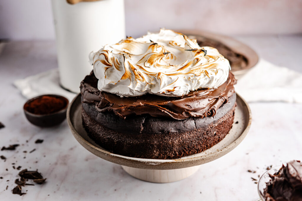 Ein einfaches Rezept für einen super saftigen und fudgy Heiße Schokoladen Kuchen. Der Boden ist wie ein Mix aus Brownie und Schokokuchen, oben drauf kommt eine samtige Schokoladen Ganache, bevor alles von flambiertem Baiser getoppt wird. #Schokoladenkuchen #Heißeschokolade #backen #Ganache #Schokolade #Baiser