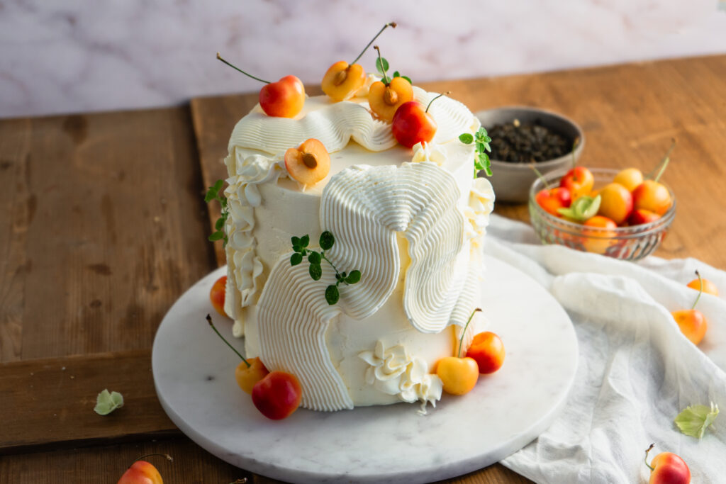 Kirsch Jasmin Mascarpone Torte mit feinen Jasminteeböden, fruchtigem Kirschkompott und cremiger Vanille-Mascarponefüllung. Eine elegante Sommertorte mit zartem Teearoma, frischen Kirschen und geschwungener Buttercreme-Dekoration – besonders schön für festliche Kaffeetafeln, Geburtstage und sommerliche Anlässe. #kirschtorte #tortenrezept #mascarponecreme #jasminttee #sommertorte #geburtstagstorte #backen #kirschrezept #buttercreme #foodphotography