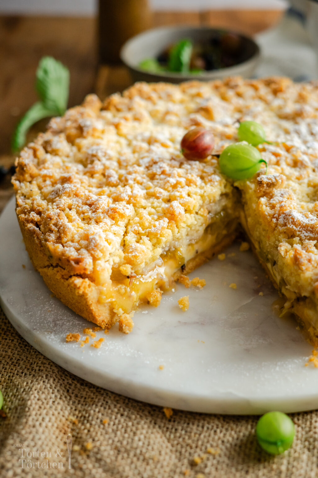 Stachelbeer Streuselkuchen mit cremiger Vanillepuddingfüllung, frischen Stachelbeeren und buttrigen Streuseln. Ein einfacher, saftiger Obstkuchen mit knuspriger Decke und fruchtig-säuerlicher Füllung, perfekt für den Sommer und wenn man mal zu viele Stachelbeeren geerntet hat! #stachelbeerkuchen #streuselkuchen #obstkuchen #sommerkuchen #puddingkuchen #backen #kuchenrezept #stachelbeeren #kaffeetafel #einfachbacken