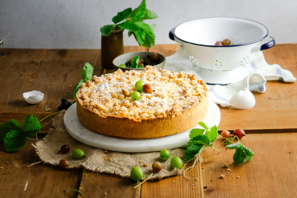 Stachelbeer Streuselkuchen mit cremiger Vanillepuddingfüllung, frischen Stachelbeeren und buttrigen Streuseln. Ein einfacher, saftiger Obstkuchen mit knuspriger Decke und fruchtig-säuerlicher Füllung, perfekt für den Sommer und wenn man mal zu viele Stachelbeeren geerntet hat! #stachelbeerkuchen #streuselkuchen #obstkuchen #sommerkuchen #puddingkuchen #backen #kuchenrezept #stachelbeeren #kaffeetafel #einfachbacken